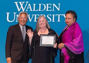 Dr. Nadine Lukes-Dyer (center) receives the Outstanding Alumni Award from Board of Directors Chair Toni Freeman (right) and board member John Kobara (left).